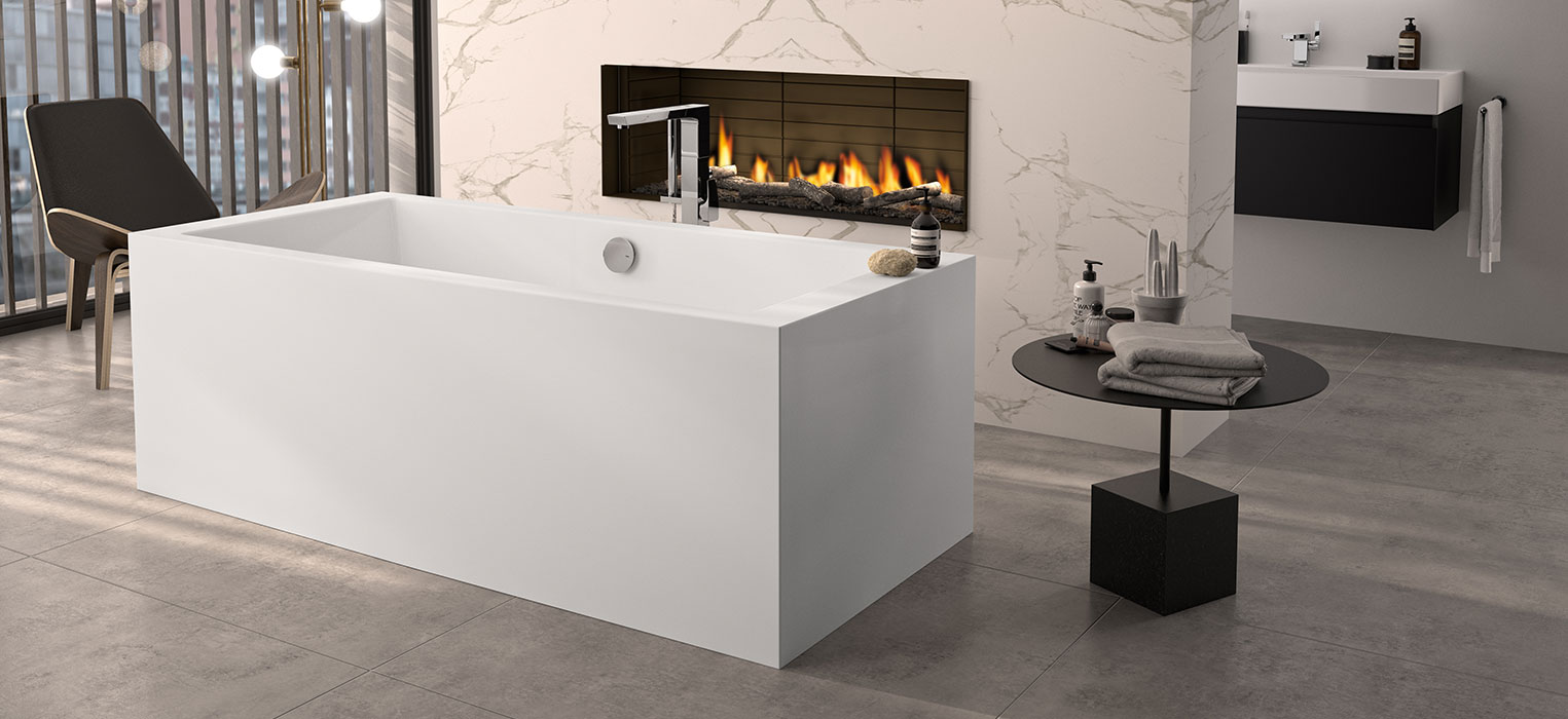 Ein modernes Badezimmer mit einer freistehenden Badewanne, einem beleuchteten Kamin in einer Marmorwand, einem schwarzen Stuhl an großen Fenstern und einem kleinen runden Tisch mit Handtüchern und Toilettenartikeln auf einem grauen Fliesenboden.