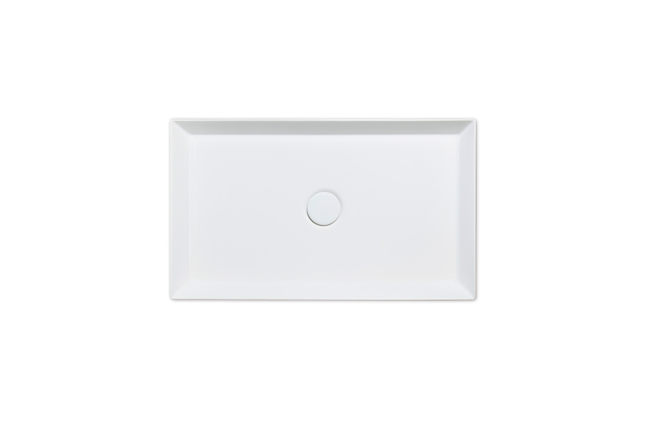 Rechteckiges weißes Waschbecken mit flachem Boden und leicht abgeschrägten Seiten, von oben gesehen. Ein kreisförmiger Abfluss befindet sich in der Mitte des Bodens. Der Hintergrund ist einfarbig weiß.