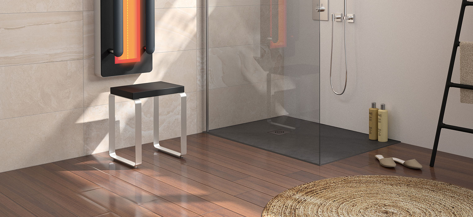 Modernes Badezimmer mit Holzboden, rundem Webteppich, gläserner Dusche, an der Wand montierten Bedienelementen für die Dusche, beheiztem Handtuchhalter, schwarzer Bank, Regal in Leiterform und zwei Flaschen auf dem Boden.