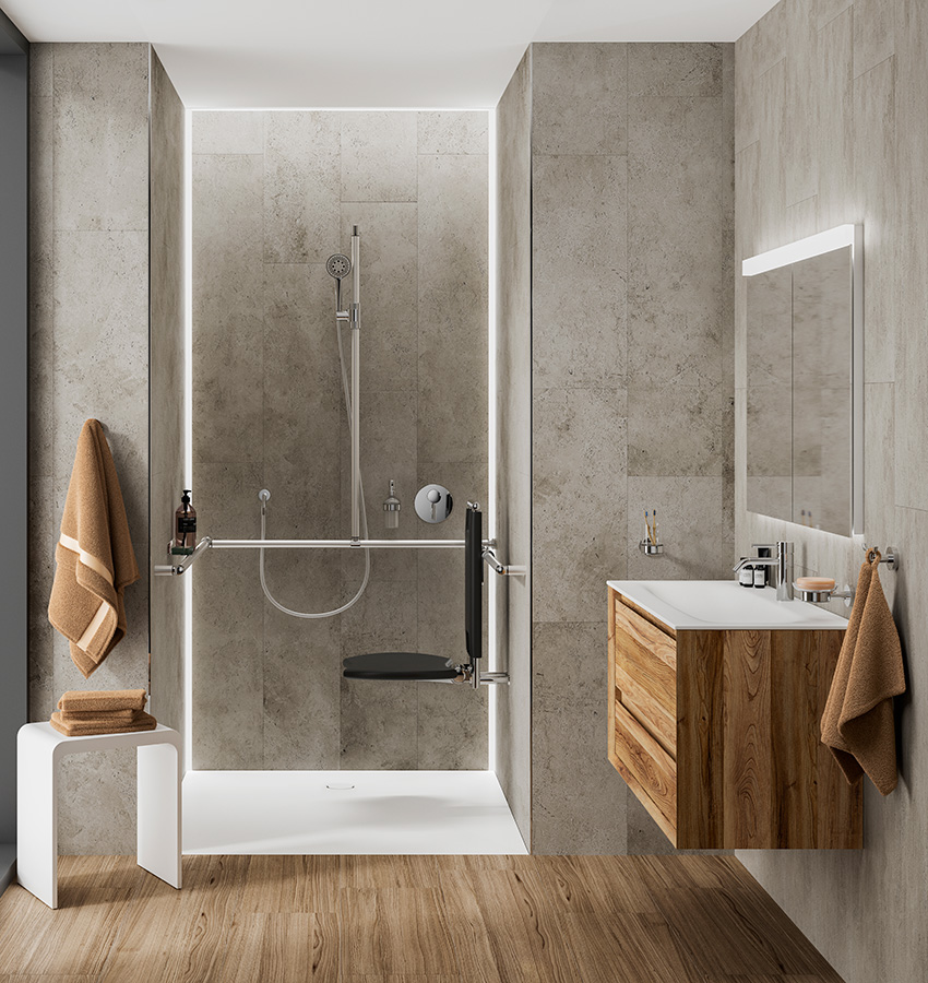 Modernes, barrierefreies Bad mit hellbraunen Fliesenwänden und Holzfußböden. Ausgestattet mit einer begehbaren Dusche mit Haltegriffen - ein Design, das in Weiterbildung SHK oft hervorgehoben wird - sowie einem schwarzen Duschsitz, braunen Handtüchern, einem Waschbecken aus Holz und einem beleuchteten Spiegel.